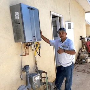 Technician beside exterior tankless installation