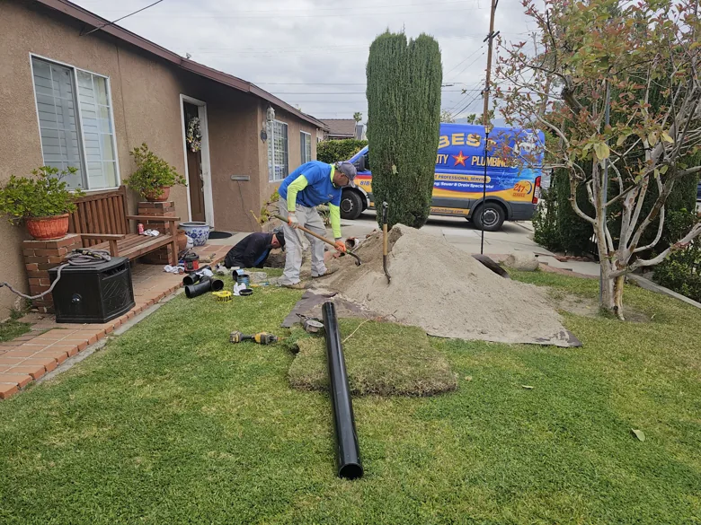 Technician beside lawn excavation and replacement pipe