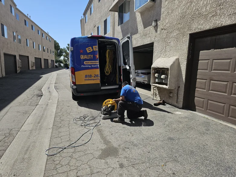 Technician using drain equipment beside van in shared driveway