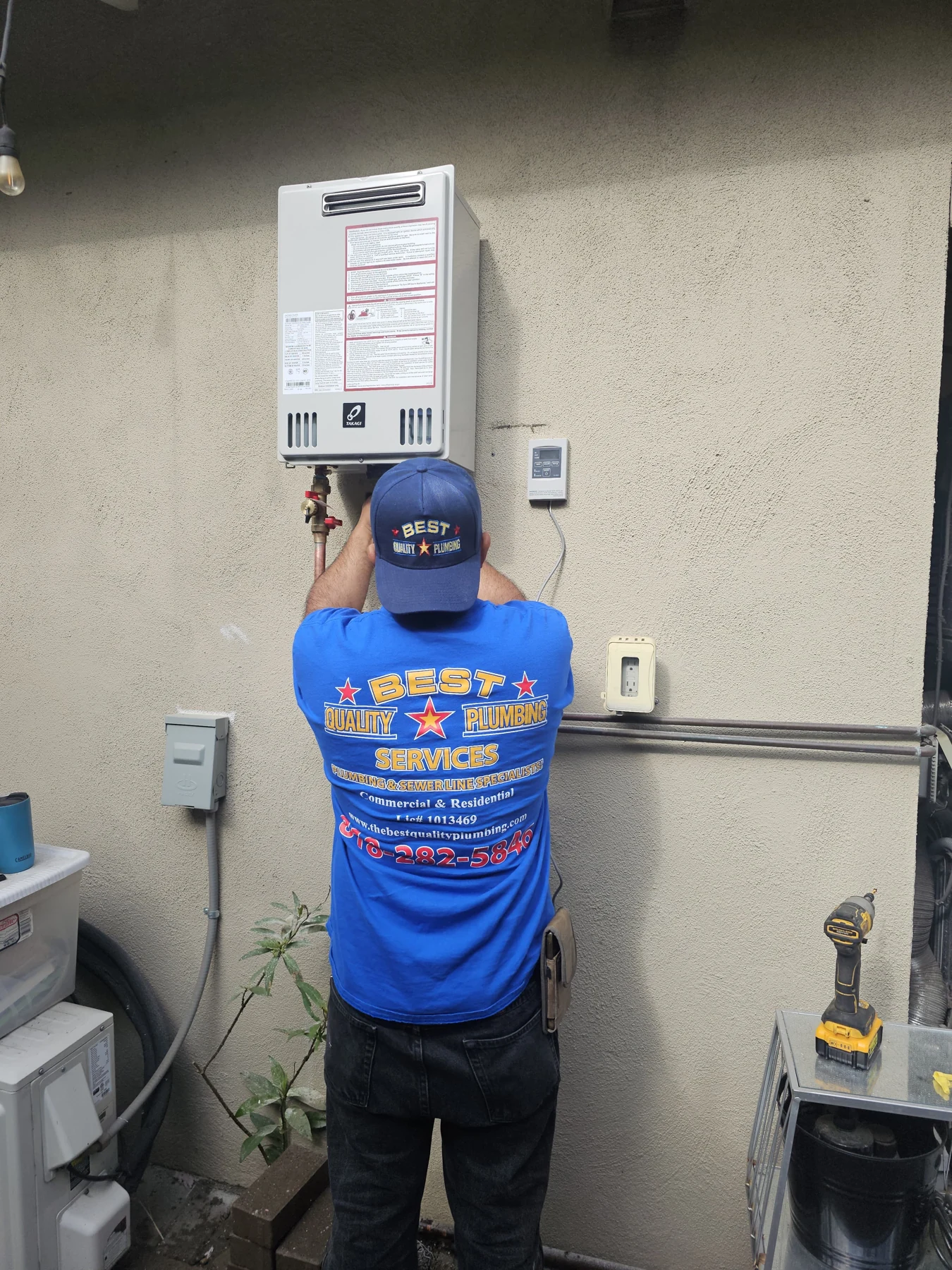 Branded technician working on wall-mounted tankless heater