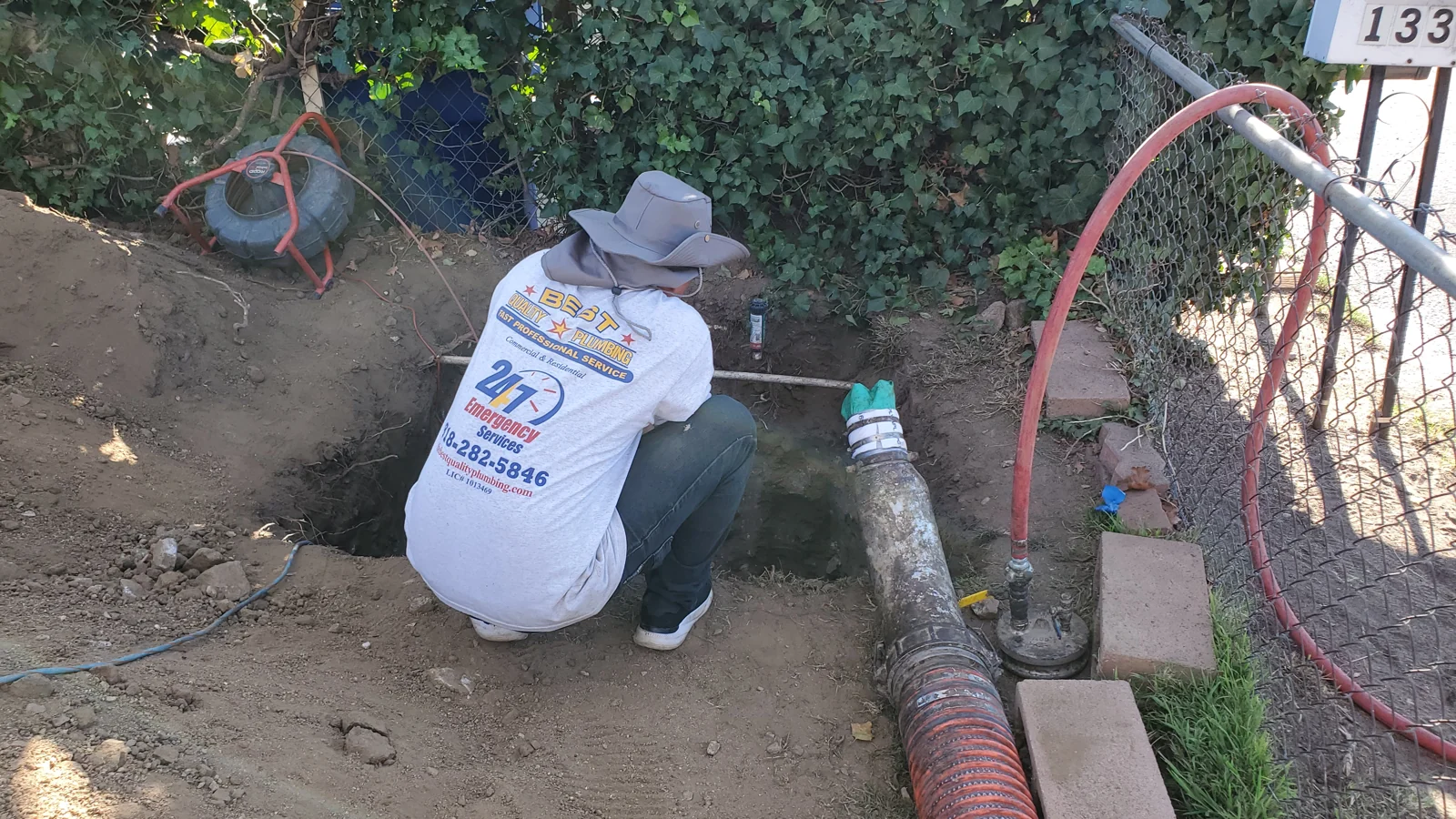 Plumber working on an exposed underground sewer line