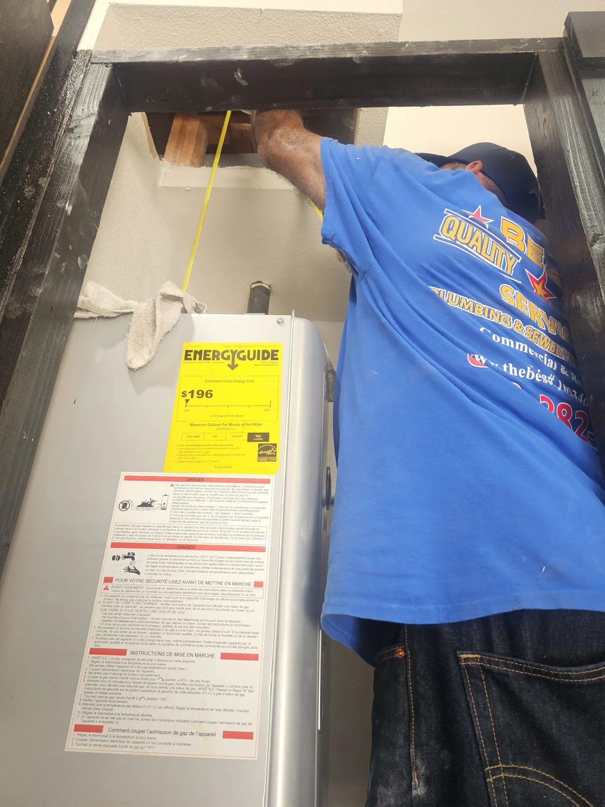 Plumber servicing a storage water heater in a utility closet